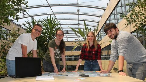 Dein erster Tag 4 junge Menschen über einen Tisch gebeugt